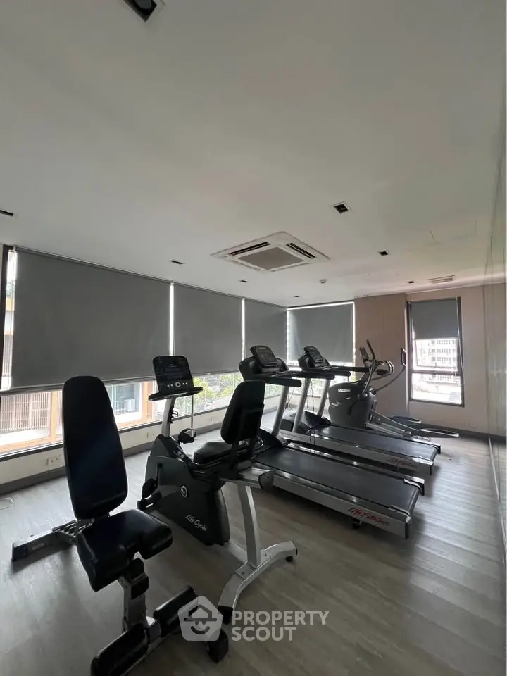 Modern gym with exercise equipment and large windows in a residential building.