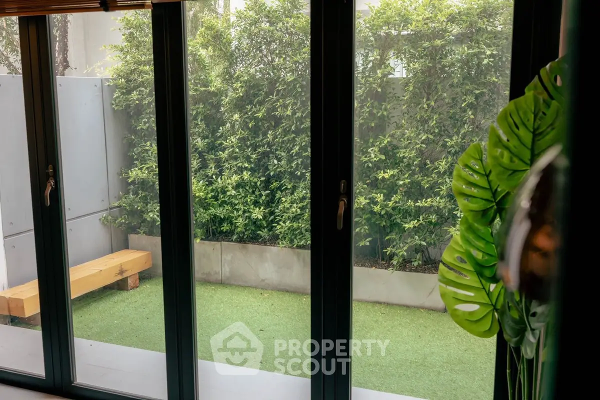 Charming garden view through large glass doors with lush greenery and modern design.