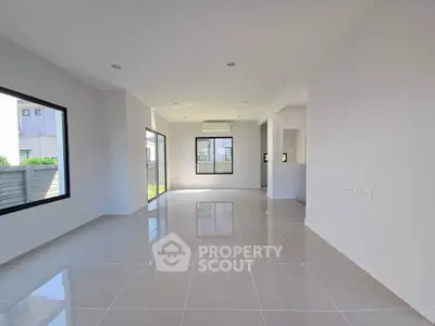 Spacious modern living room with large windows and glossy tiled floors.