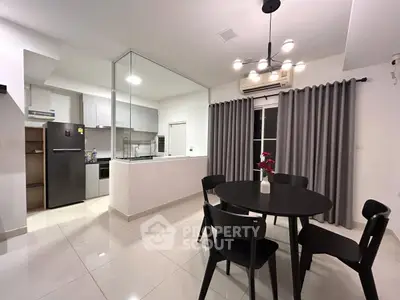 Modern open-layout kitchen and dining area with sleek design and contemporary lighting.