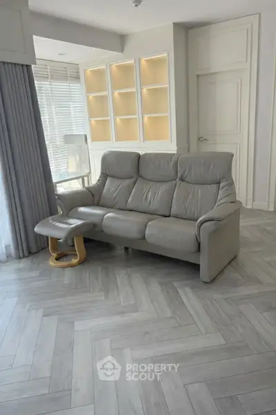 Modern living room with sleek gray sofa and elegant herringbone flooring