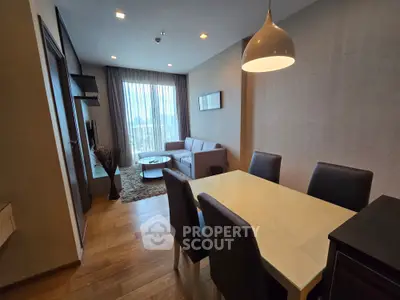 Modern living room with dining area, featuring stylish furniture and large window with city view.