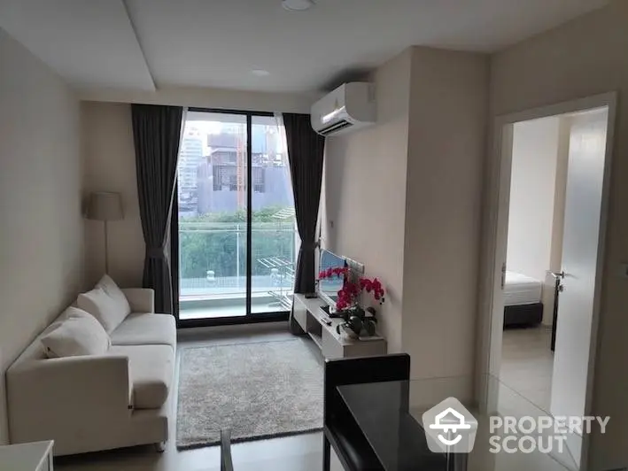 Modern apartment living room with natural light, sleek furniture, and balcony access, perfect for urban living.