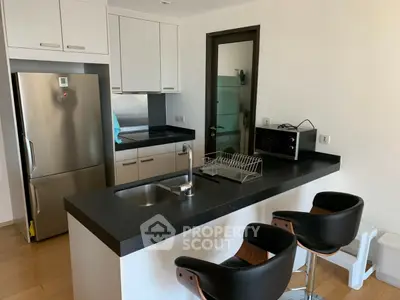 Modern kitchen with sleek black countertops and stainless steel appliances in a contemporary apartment.