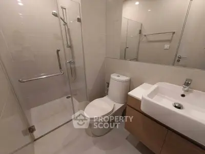 Modern bathroom with glass shower and sleek fixtures in contemporary apartment.