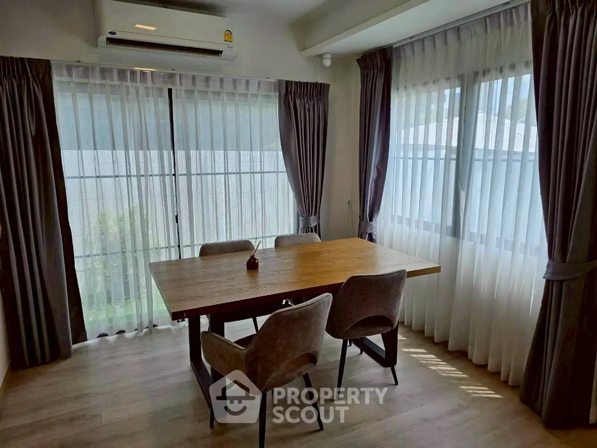 Elegant dining area with natural light, featuring a wooden table and modern chairs, perfect for intimate gatherings.