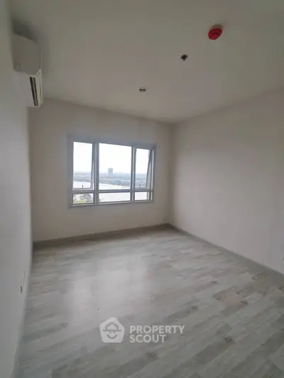 Spacious empty room with large window offering stunning city view, perfect for customization.