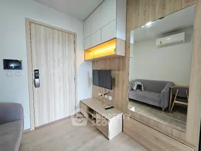 Modern living room with sleek furniture and wall-mounted TV in cozy apartment.