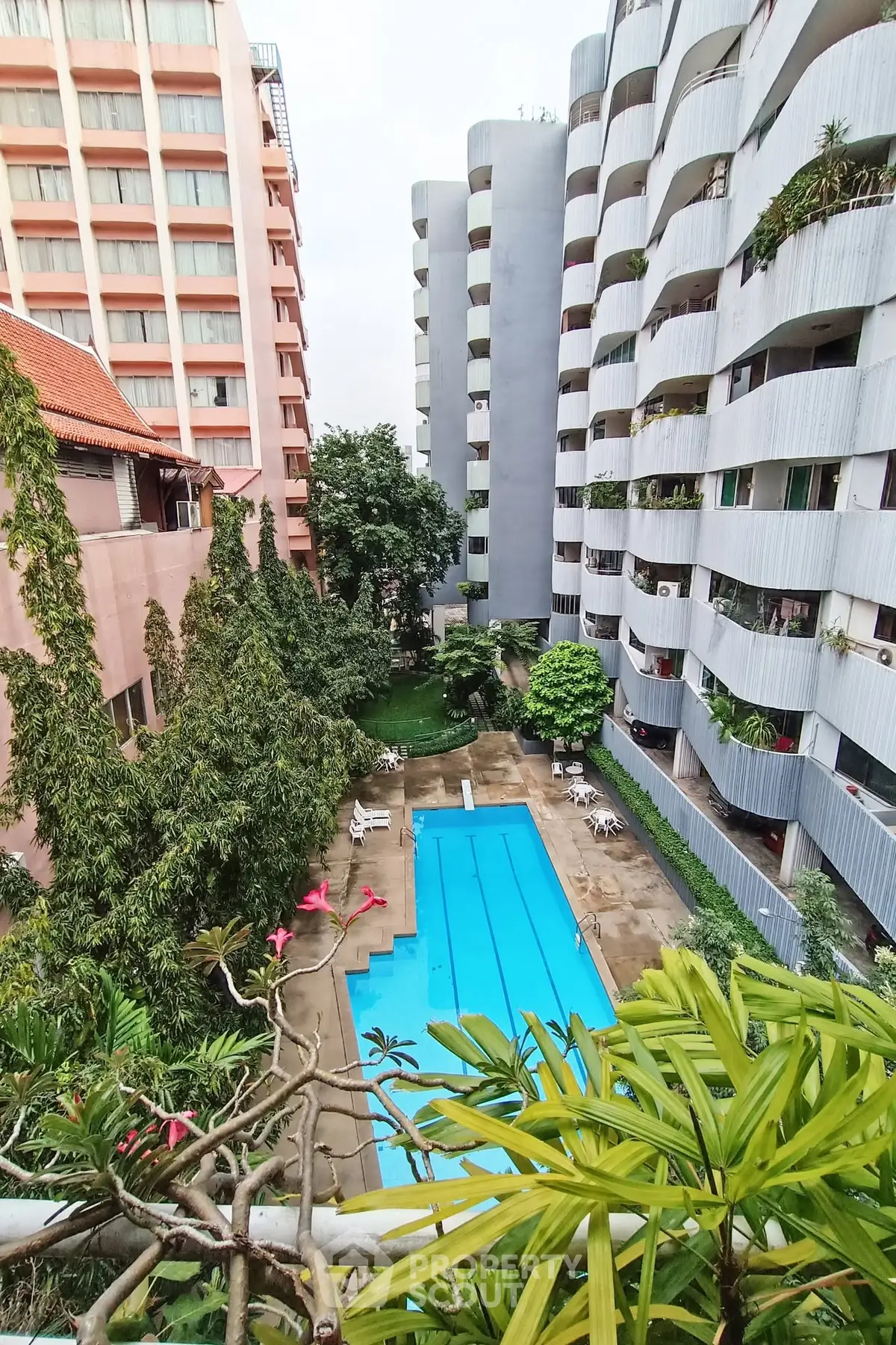 Stunning view of modern apartment complex with pool and lush greenery
