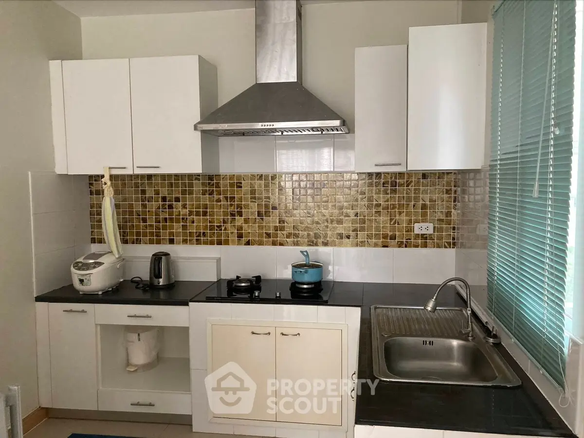 Modern kitchen with sleek cabinets and stylish backsplash, featuring gas stove and stainless steel sink.