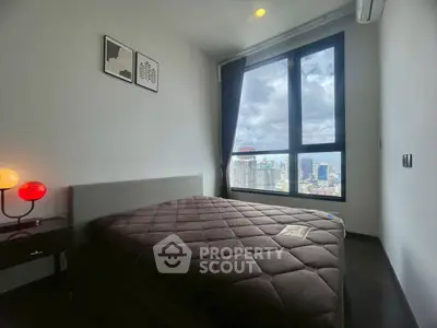 Modern bedroom with large window offering stunning city views, featuring cozy bed and stylish decor.
