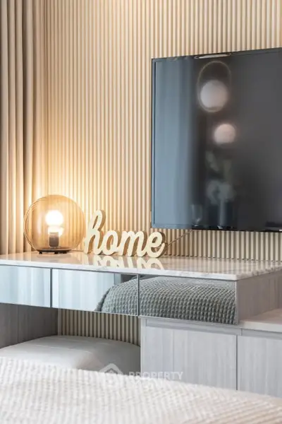 Modern living room with stylish decor and flat-screen TV, featuring elegant lighting and cozy ambiance.