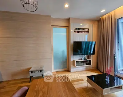 Modern living room with sleek wooden finishes and mounted TV, featuring elegant decor and natural light.