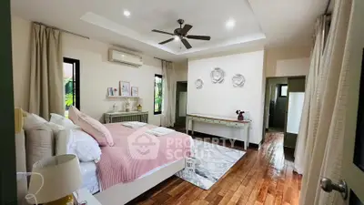 Spacious bedroom with elegant decor and wooden flooring in a modern home.