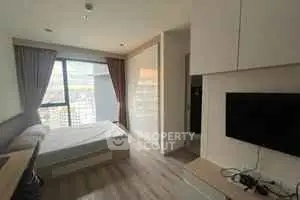 Modern bedroom with large window and sleek furnishings in a high-rise apartment.