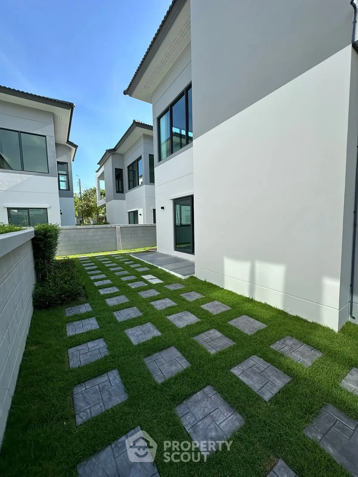 Modern minimalist exterior with sleek design and lush green lawn in a contemporary residential area.
