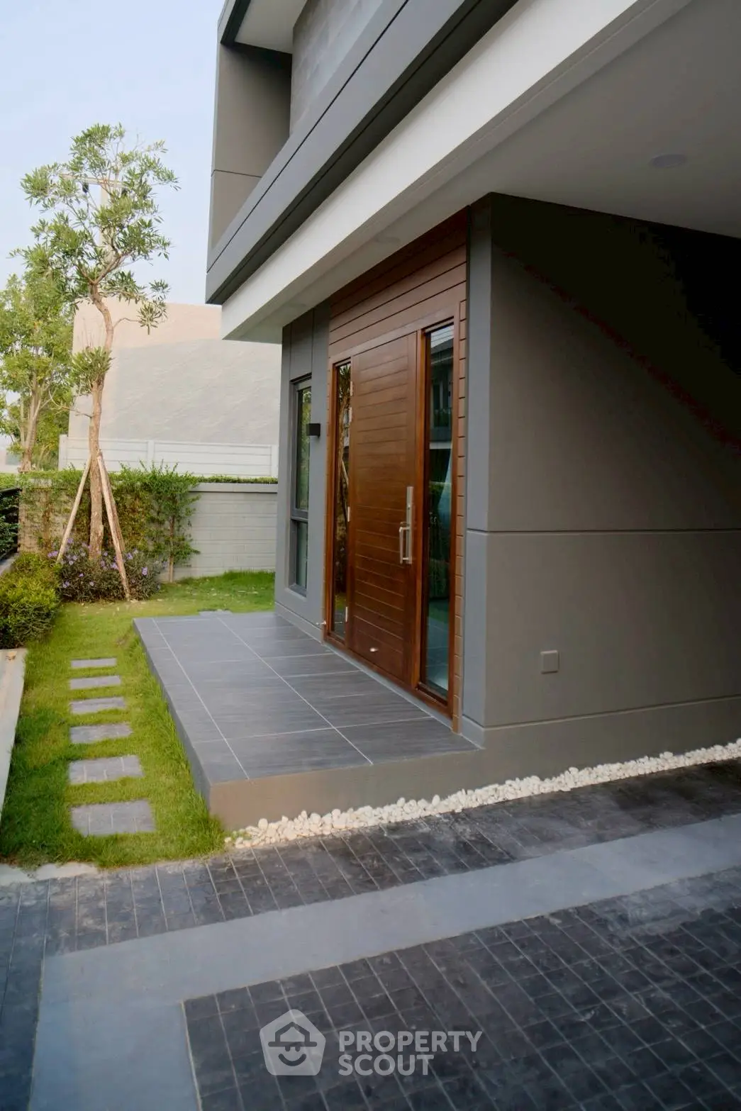 Modern house entrance with sleek wooden door and landscaped pathway