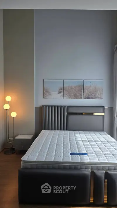 Modern bedroom with stylish decor and comfortable mattress, featuring elegant lighting and serene artwork.
