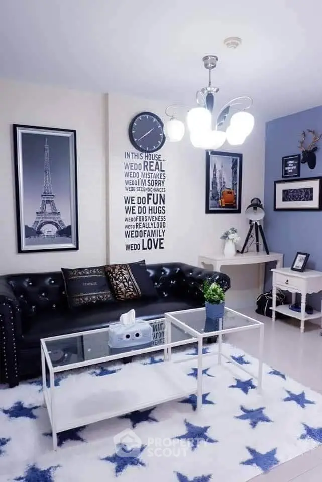 Stylish living room with modern decor, featuring a black leather sofa, glass coffee table, and chic wall art.
