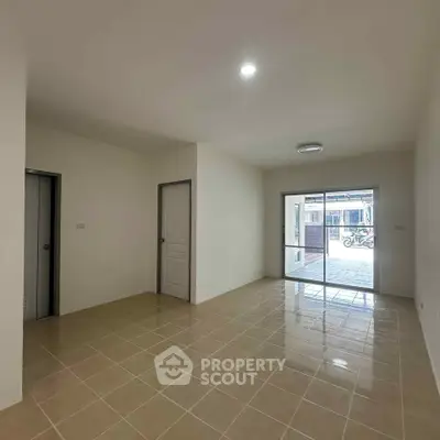 Spacious unfurnished living room with tiled flooring and large window for natural light.