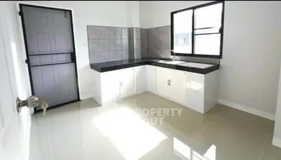 Modern minimalist kitchen with sleek countertops and ample natural light.