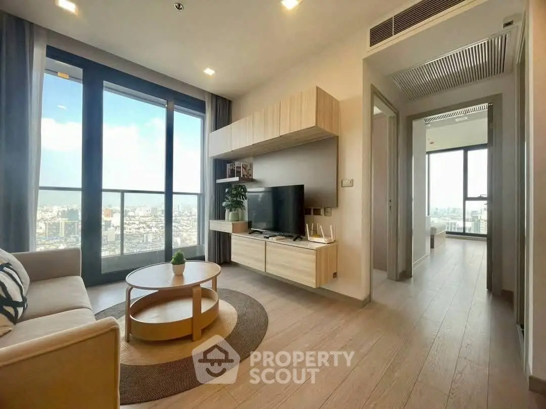Modern living room with city view, stylish furniture, and natural light in a high-rise apartment.