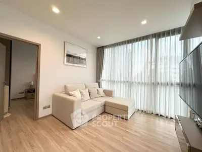 Modern living room with large windows and cozy beige sofa in a bright apartment.