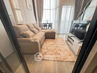 Modern living room with plush sofa and large windows offering natural light.