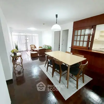 Spacious open-plan living and dining area with elegant wooden furniture and natural light.