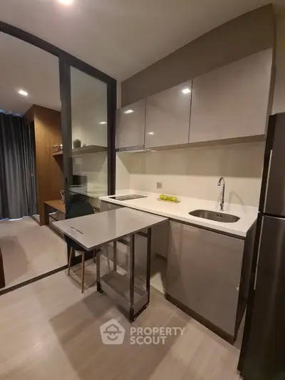 Modern compact kitchen with sleek cabinetry and integrated appliances in a stylish apartment.