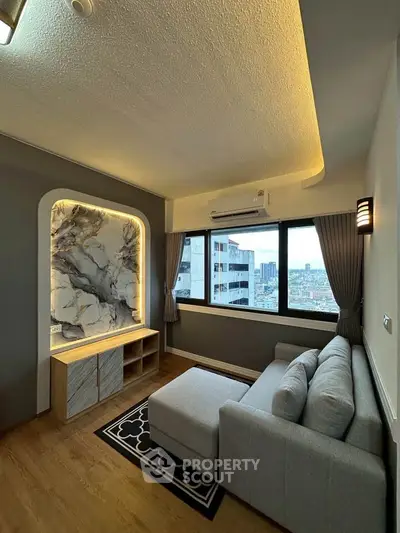 Modern living room with stylish marble accent wall and city view, featuring a cozy gray sofa and wooden flooring.