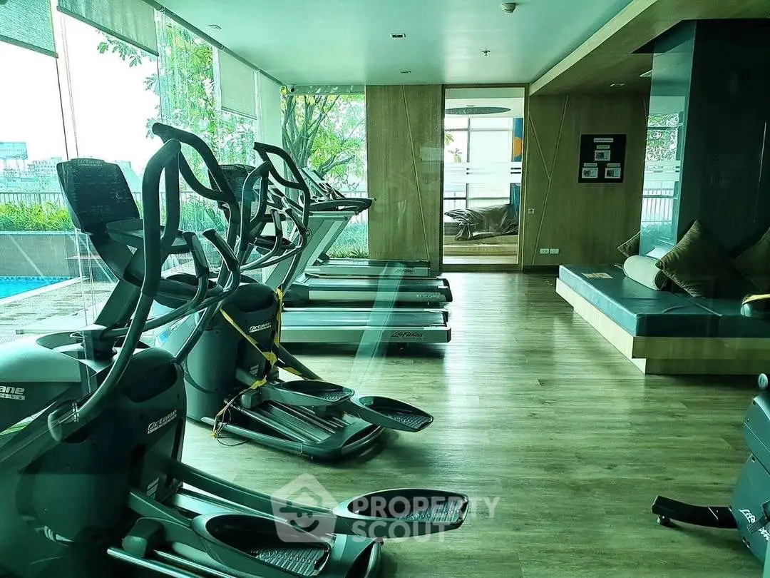 Modern gym with state-of-the-art equipment and pool view in luxury real estate property.
