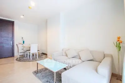 Spacious modern living room with cozy sofa and dining area in open layout apartment.