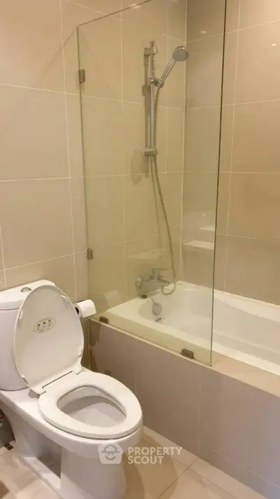 Modern bathroom with glass-enclosed bathtub and sleek fixtures.