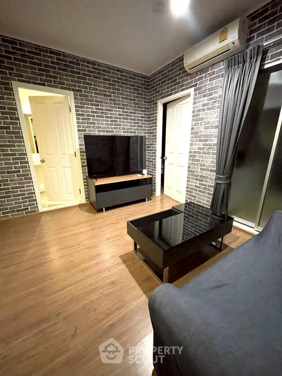 Modern living room with brick walls, sleek furniture, and wooden flooring