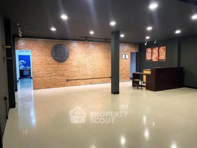 Spacious modern interior with brick accent wall and sleek lighting, ideal for versatile use.