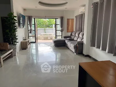 Spacious living room with modern furniture and large windows opening to a patio.