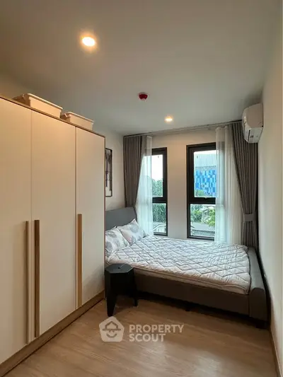 Cozy bedroom with modern decor, featuring a large window and ample natural light.
