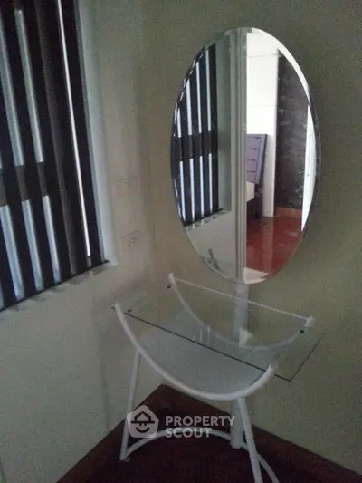 Stylish bedroom corner with modern mirror and glass table