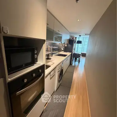 Modern kitchen with sleek appliances and wooden flooring in a stylish apartment.
