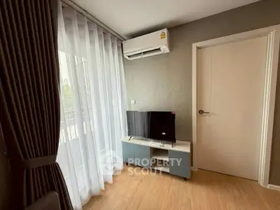 Cozy living room with modern TV setup and natural light from large window.