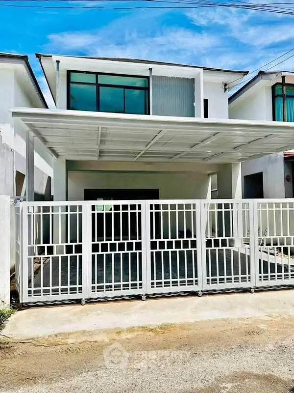 Modern two-story house with sleek design and gated entrance in a sunny neighborhood.