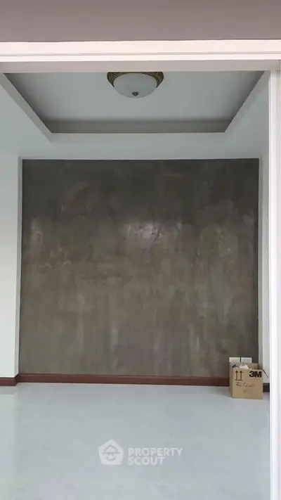 Modern minimalist interior with polished concrete accent wall and recessed ceiling lighting.