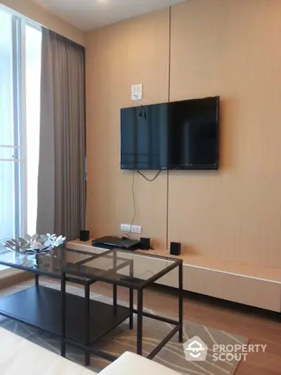 Modern living room with wall-mounted TV, glass coffee table, and floor-to-ceiling window draped in elegant curtains.