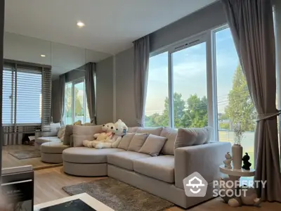 Spacious living room with plush sofa and large windows offering serene views