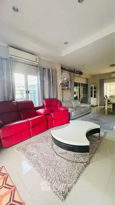 Spacious living room with modern red and gray sofas, stylish coffee table, and large windows for natural light.