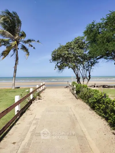 Stunning beachfront view with lush greenery and clear blue skies, perfect for serene coastal living.