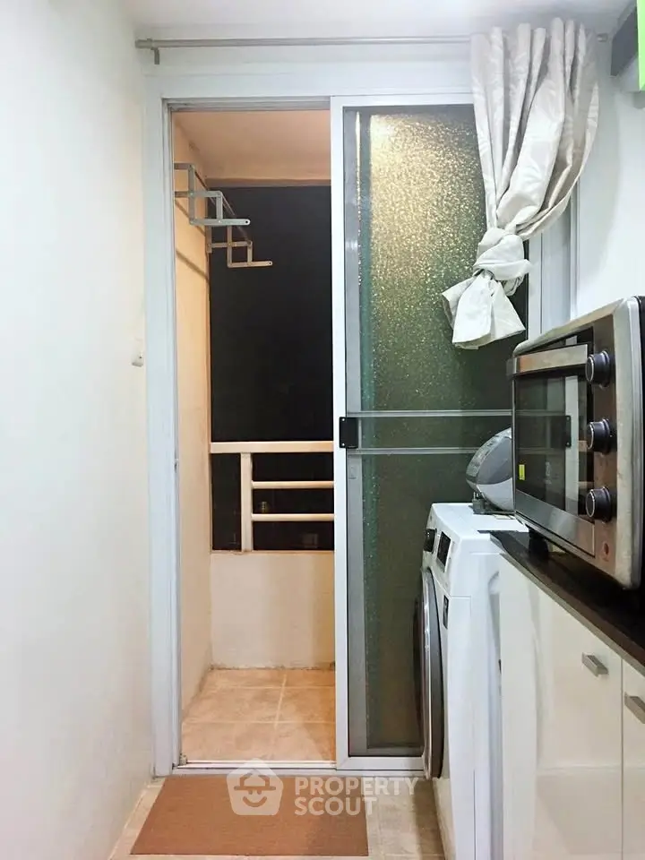 Compact kitchen with modern appliances and sliding door to small balcony.
