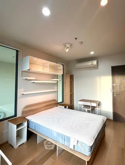 Modern bedroom with wooden flooring, stylish bed, and ample natural light in a contemporary apartment.