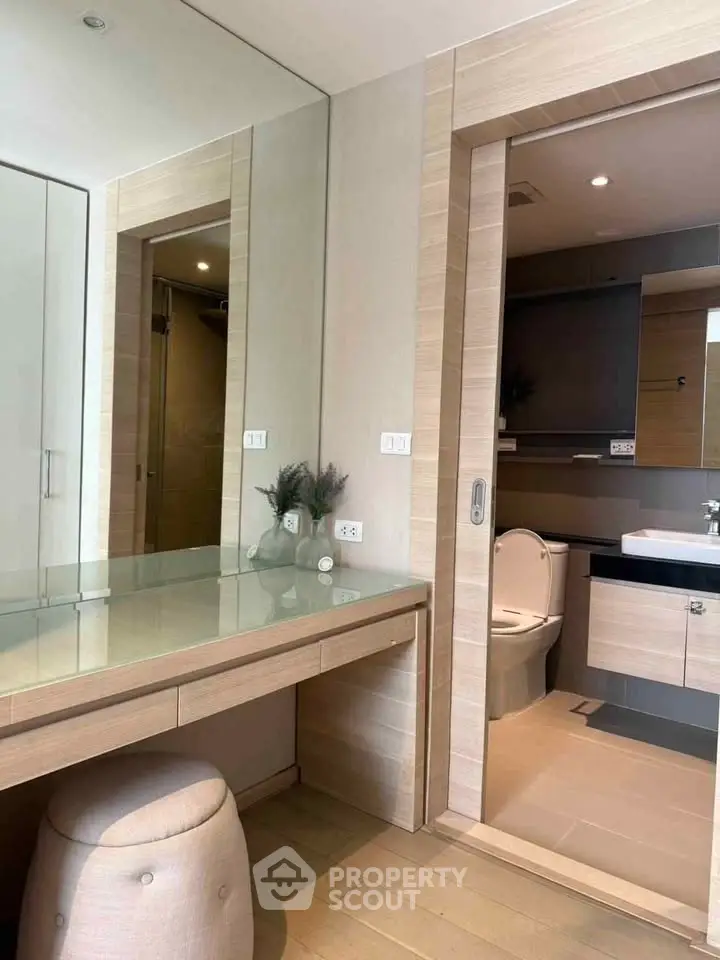 Modern bathroom with sleek design and wooden accents, featuring a vanity and glass shower enclosure.
